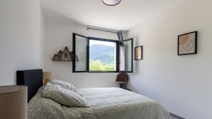 Ein Schlafzimmer mit Bett, Fenster, Lampe und einem Wandregal.