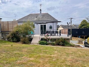 Ein Haus mit überdachter Terrasse, Sitzgelegenheiten im Freien und einem Garten.