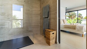 A modern bathroom with a glass shower enclosure, a wooden basket, and a large window. - Villa Camarines, new villa, pool, walk to beach (Agde)