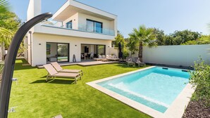 A modern two-story house with a swimming pool, outdoor seating, and a well-maintained lawn. - Villa Camarines, new villa, pool, walk to beach (Agde)