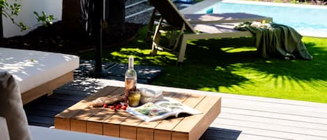 Una terraza de madera con una mesa dispuesta para una comida, una botella y un libro.