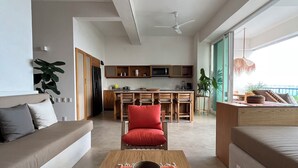 A modern living room with a sofa, a dining area, and a kitchen in the background. - Casa Mamita | Spectacular ocean view | Terrace with private hot tub and pool (Puerto Escondido)