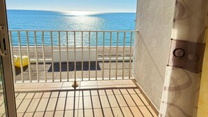 Ein Balkon mit Blick auf das Meer, einem weißen Geländer und einem gelben Stuhl.