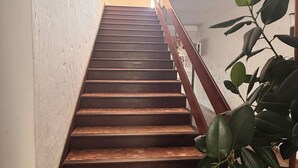 Eine Treppe mit Holzstufen und einem Metallgeländer, die zu einer Zwischenebene mit einer Pflanze führt.