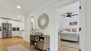 A modern kitchen with white cabinets, a wooden console table, and a decorative mirror.