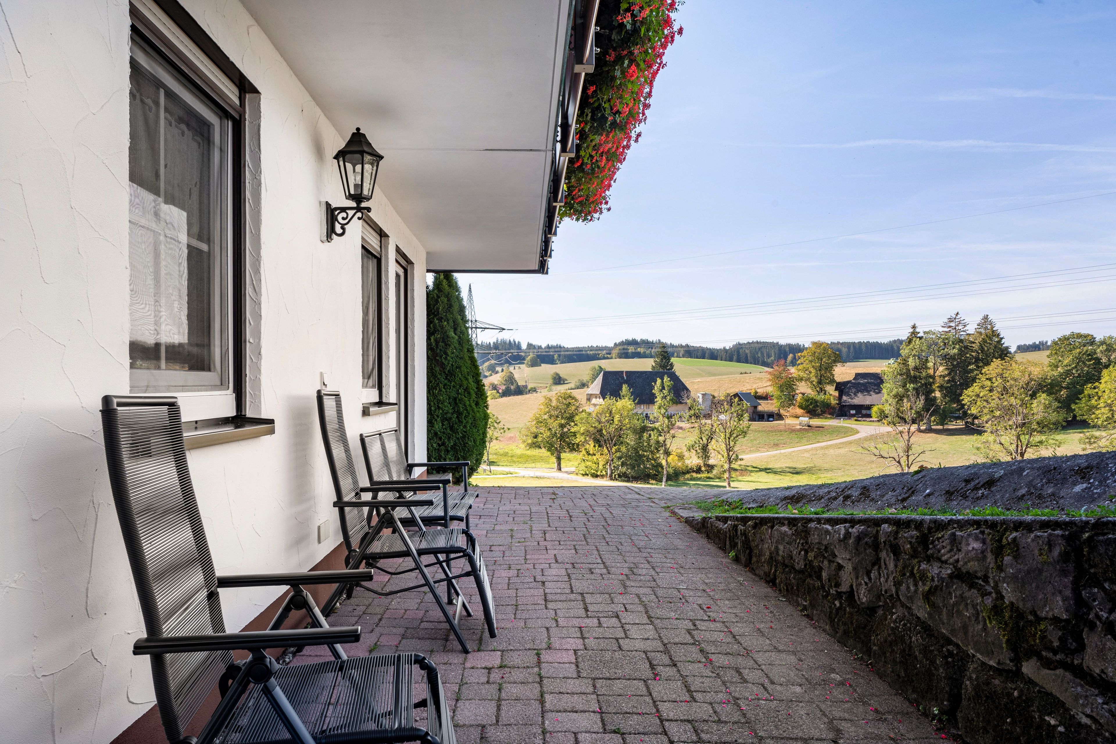 Un bâtiment doté d’un balcon, d’un espace extérieur aménagé pour s’asseoir et offrant une vue sur un paysage rural.