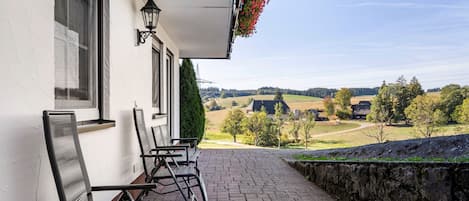 Un edificio con balcón, mobiliario exterior y vistas a un paisaje rural.