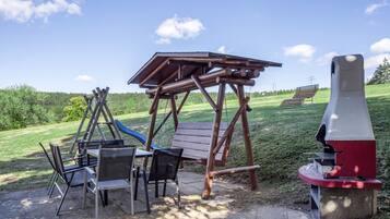 Ein Spielplatz mit Schaukel, Rutsche und Bank.