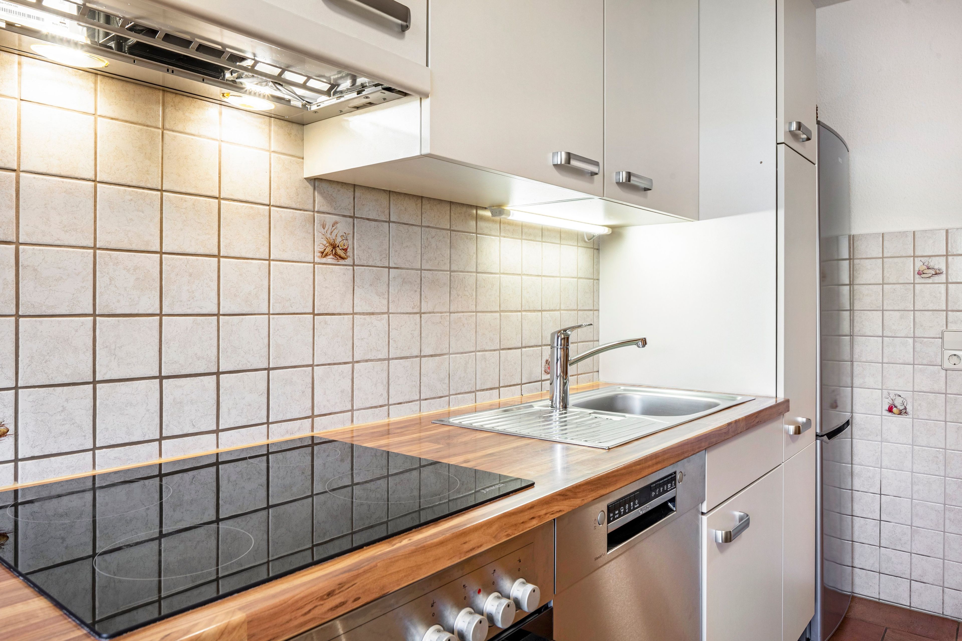 A modern kitchen with a built-in stove, a sink, and stainless steel appliances.