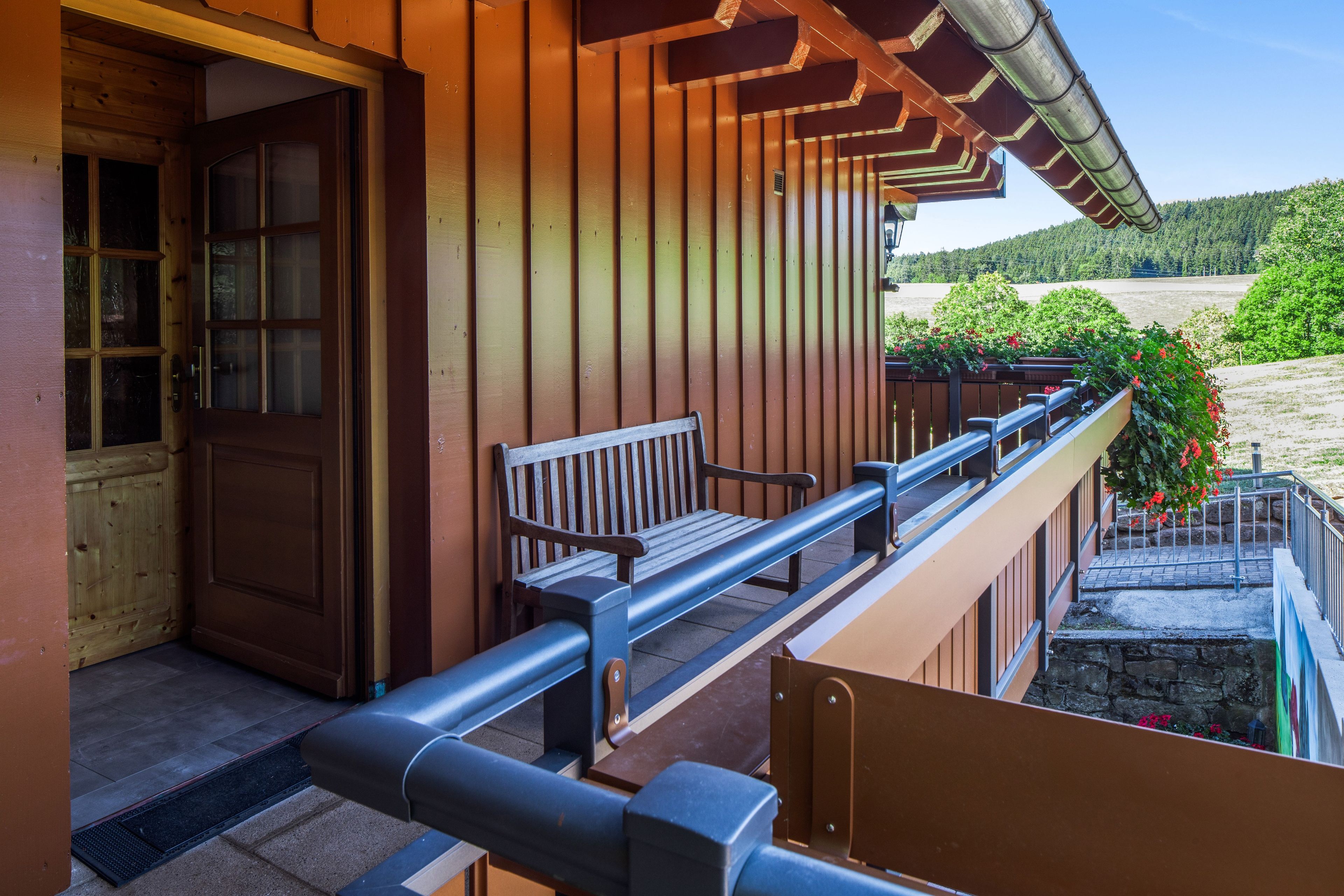 A wooden building with a balcony, a bench, and a door.
