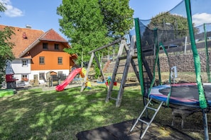 Ein Spielplatz mit Rutsche, Schaukeln und Trampolin.