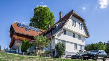 Ein zweistöckiges Haus mit geneigtem Dach, Solaranlagen und einem Auto auf der Auffahrt.