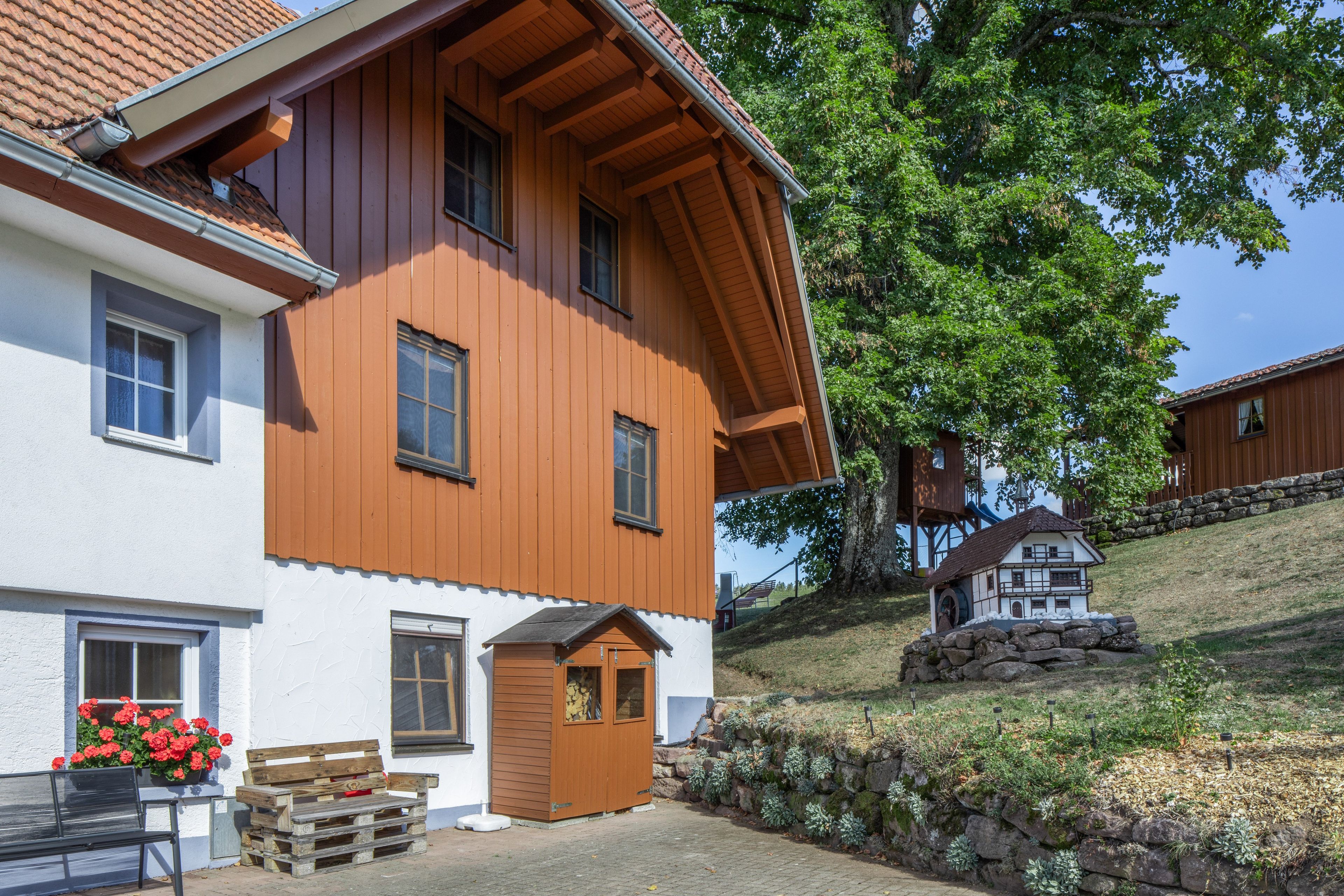 Ein zweistöckiges Haus mit geneigtem Dach, Holzverkleidung und einer kleinen Veranda.