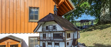 Una casa modelo de dos pisos, con balcón y base de piedra.