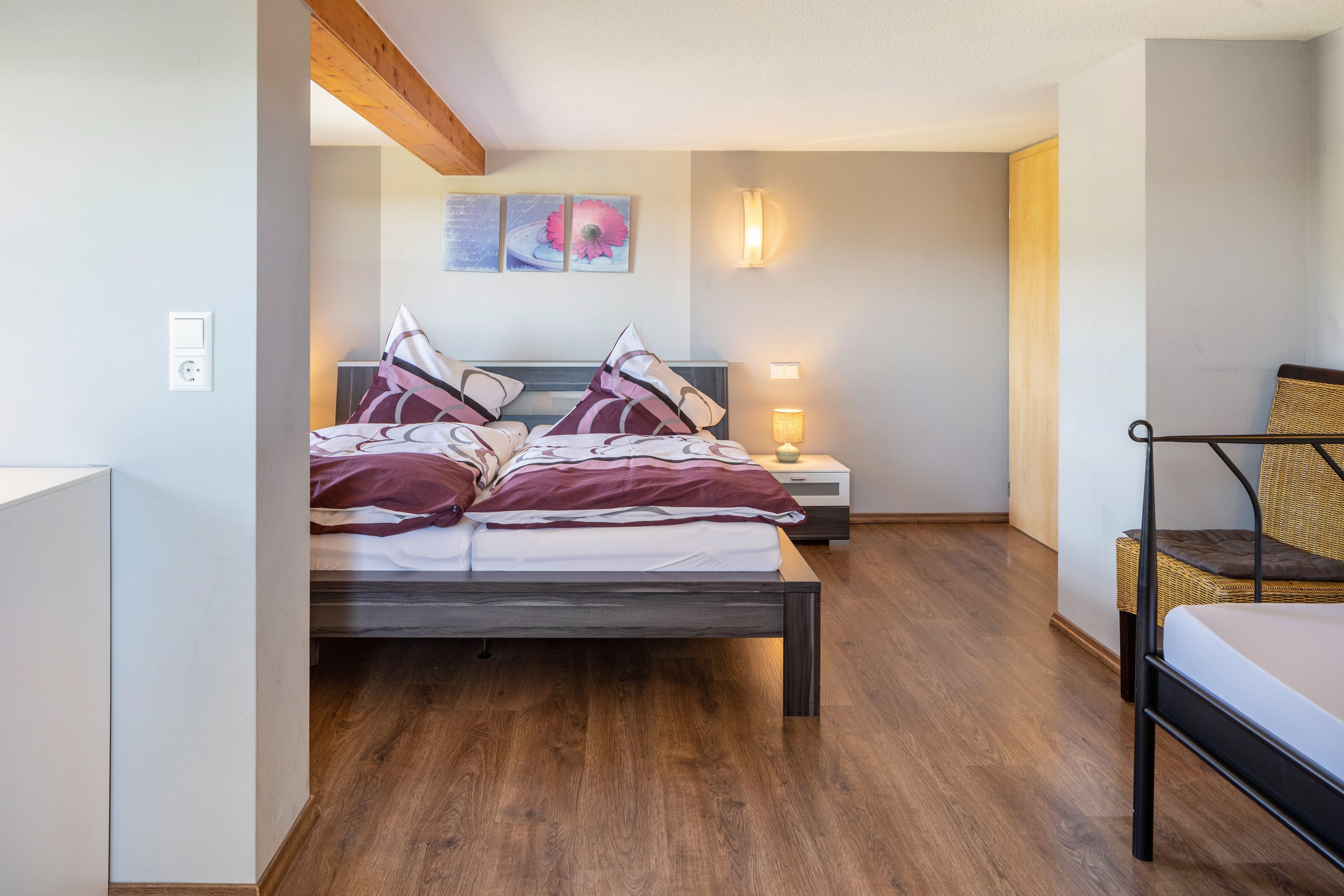 A bedroom with a bed, bedside tables, a lamp, and a chair.