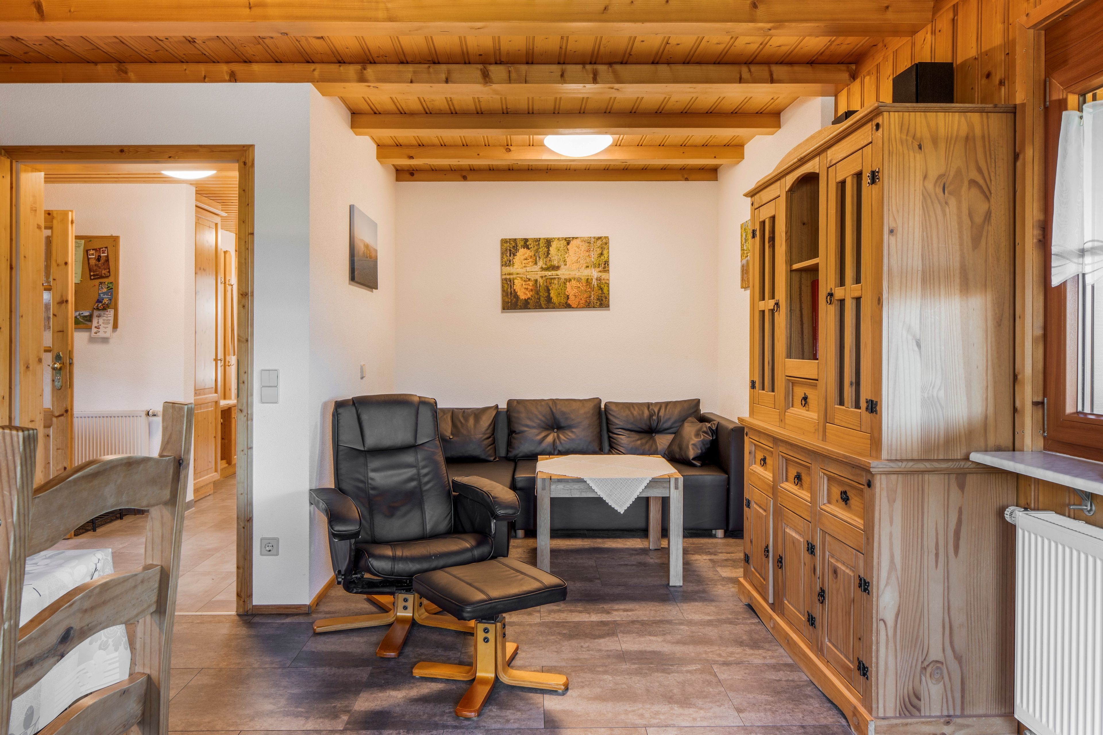 A wooden interior with a sofa, a dining table, and a cabinet.