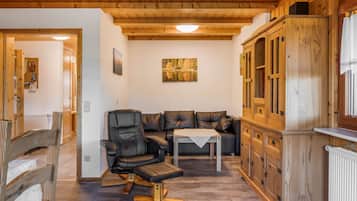 A wooden interior with a sofa, a dining table, and a cabinet.