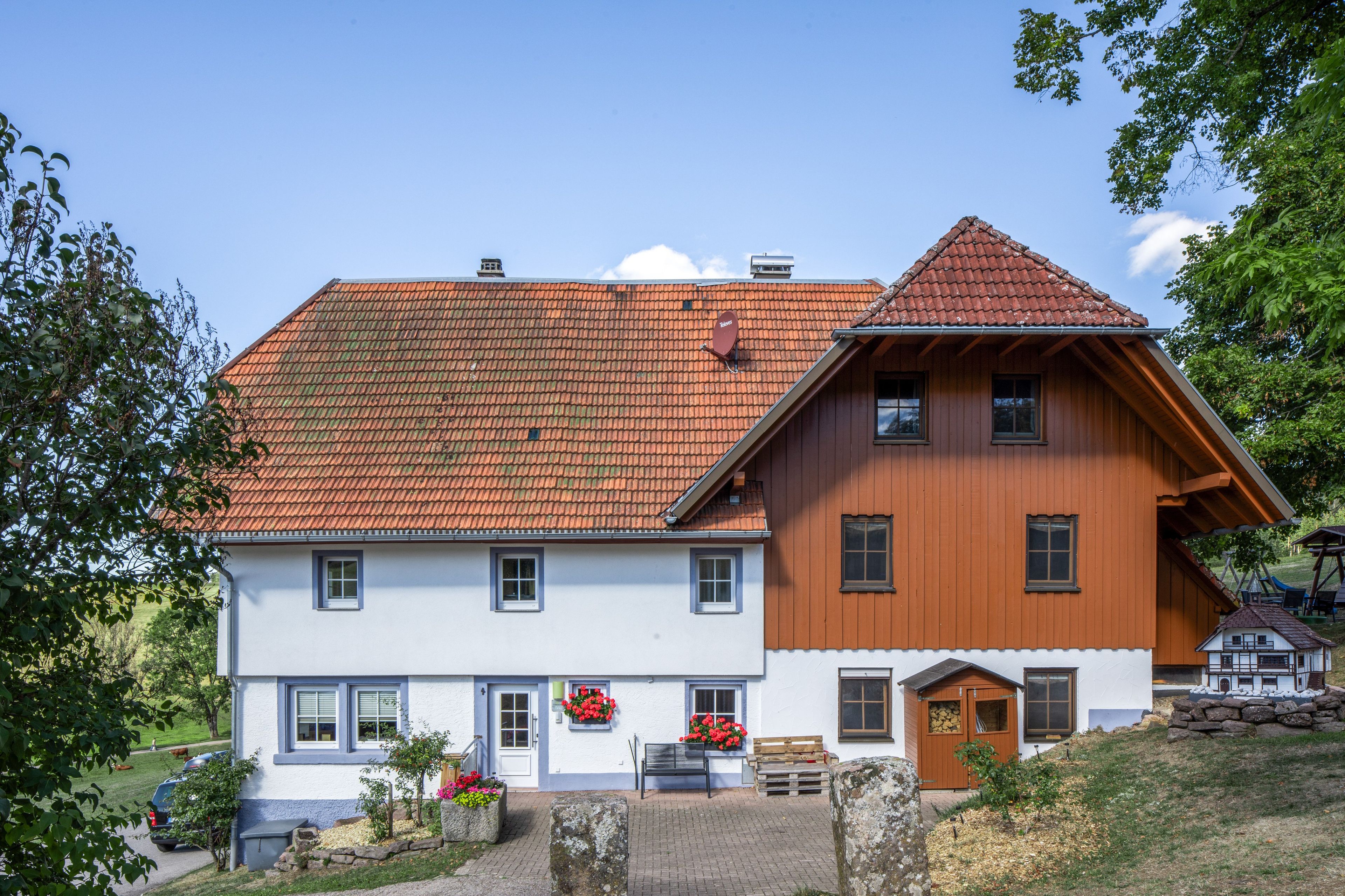 A two-story building with a red-tiled roof, white walls, and wooden accents.