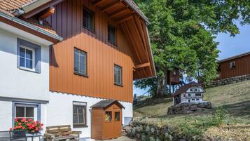 Ein zweistöckiges Haus mit geneigtem Dach, Holzverkleidung und einer kleinen Veranda.