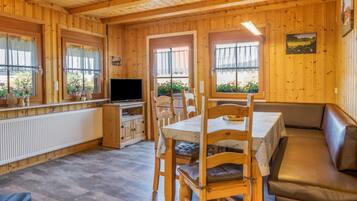A wooden interior with a dining area, seating, and a television.