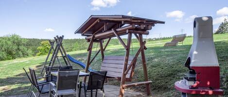 A playground with a swing set, a slide, and a bench.