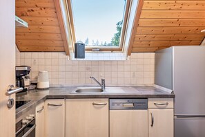 Una cocina con tragaluz, lavavajillas, cafetera y refrigerador.