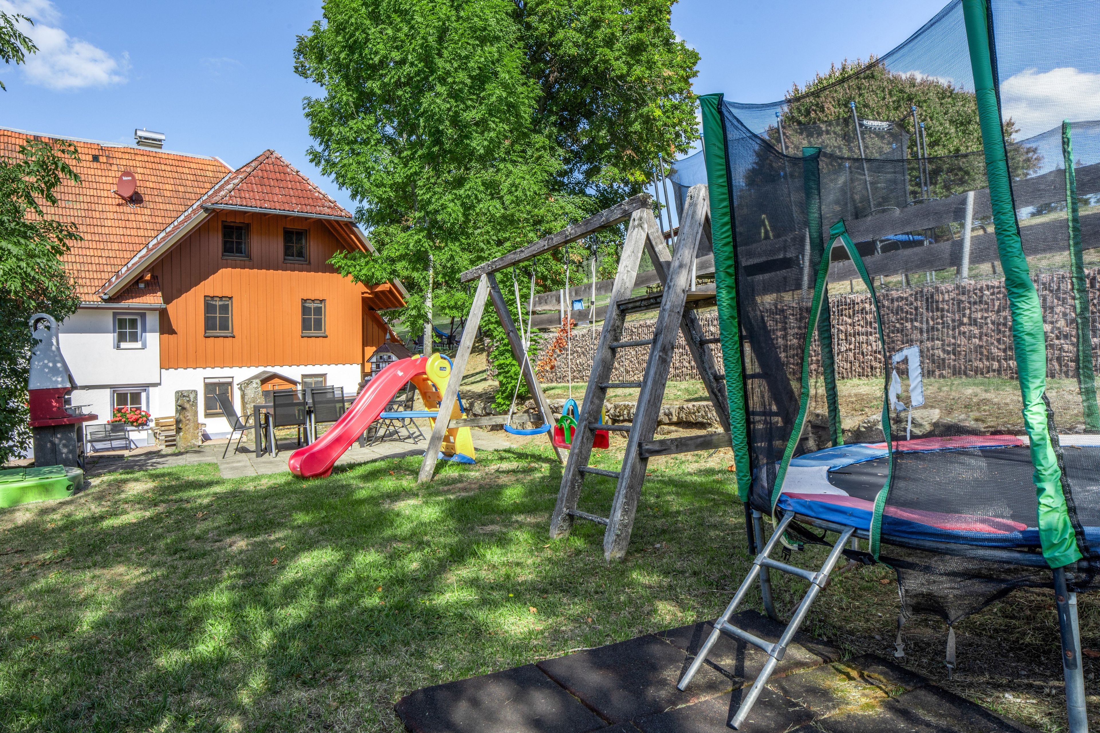 A playground with a slide, swings, and a trampoline.