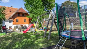 A playground with a slide, swings, and a trampoline.