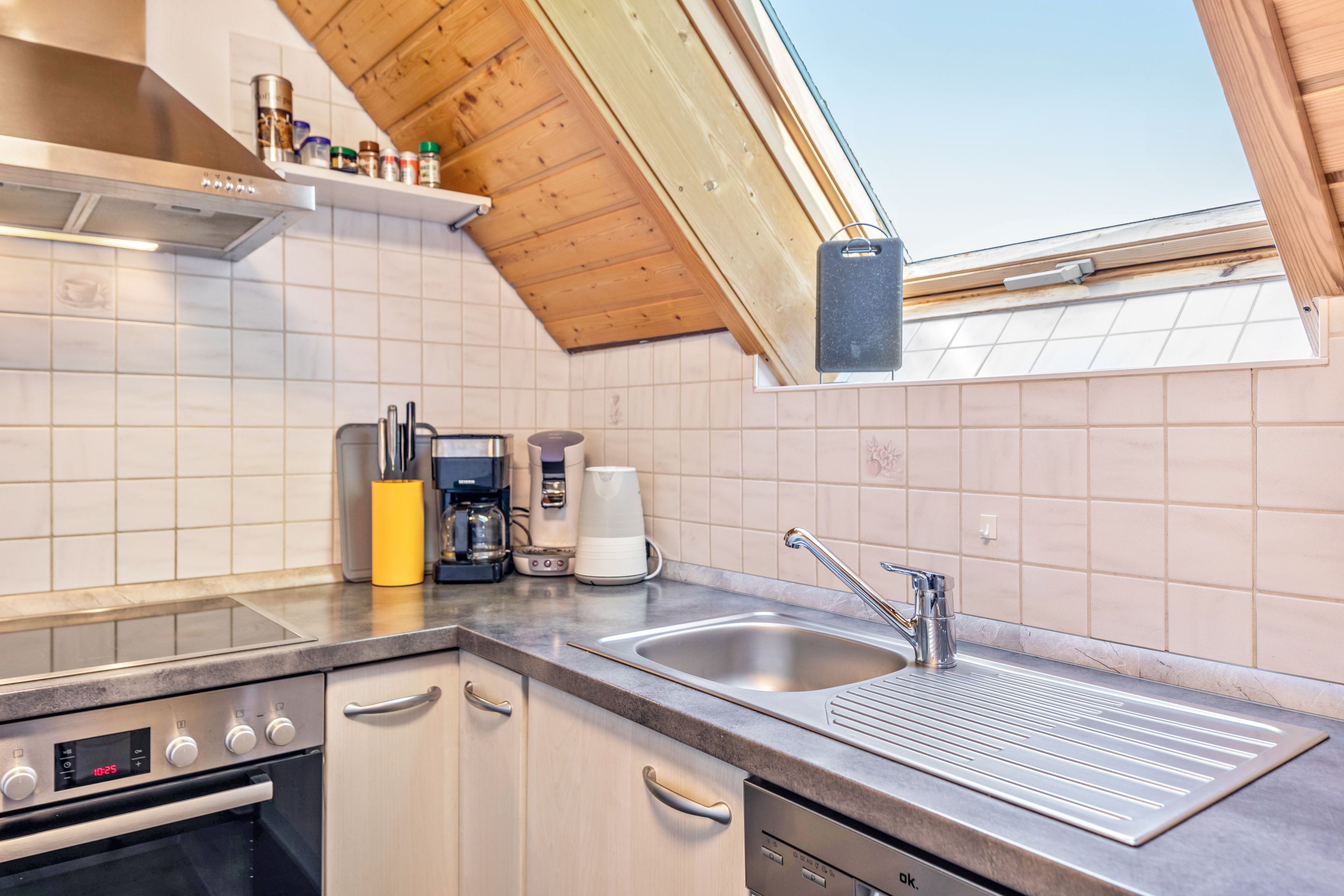 Una cocina moderna con horno integrado, cafetera y lavamanos.