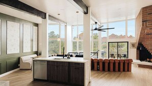 A spacious kitchen with a large island, a dining area with a high table and benches, and a fireplace. - The Doeller House | Pool, Sauna & Speakeasy (Sedona)