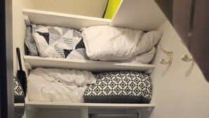Quarto compacto com beliche, radiador e pequena estante.