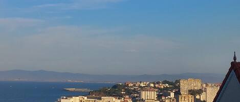 A coastal cityscape with buildings, a clear sky, and a view of the sea.