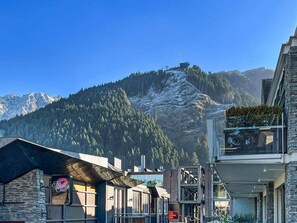 Un complejo turístico de montaña con telesilla, edificios modernos y una vista despejada de picos nevados.