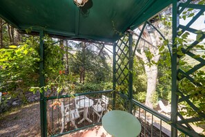 A covered outdoor seating area with a table and chairs, surrounded by greenery and trees. - Il Pulcino della Pavona - sea view and garden (Monterosso al Mare)