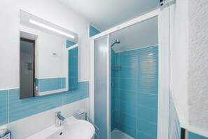 A bathroom with a white sink, a mirror, a shower enclosure, and blue-tiled walls. - Il Pulcino della Pavona - sea view and garden (Monterosso al Mare)