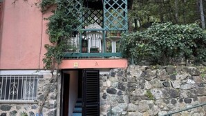 Eine Steinsäule mit einer Metalltreppe, die zu einem Balkon mit Gitterwerk führt.