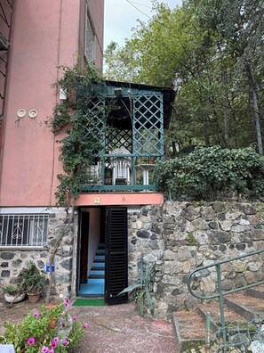 A stone wall with a metal staircase leading to a balcony with a lattice structure. - Il Pulcino della Pavona - sea view and garden (Monterosso al Mare)