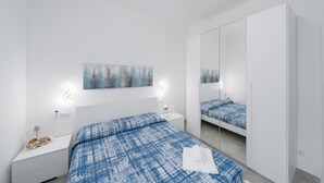 A modern bedroom with a large bed, a bedside table, a nightstand, a wardrobe, a mirror, and a wall-mounted artwork. - Charlie 89 Modern Apt with A/C in the center (Monterosso al Mare)
