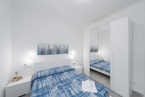 A modern bedroom with a large bed, a bedside table, a nightstand, a wardrobe, a mirror, and a wall-mounted artwork. - Charlie 89 Modern Apt with A/C in the center (Monterosso al Mare)