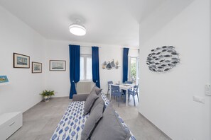 A modern room with a bed, a dining table, chairs, a radiator, and a wall art piece. - Charlie 89 Modern Apt with A/C in the center (Monterosso al Mare)