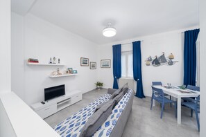 Een moderne woonkamer met een bank, televisie, eettafel en stoelen.