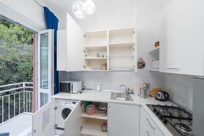 A compact kitchen with a washing machine, a microwave, and a gas stove. - Charlie 89 Modern Apt with A/C in the center (Monterosso al Mare)