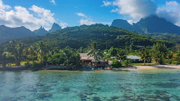 Un resort tropical con playa, aguas cristalinas y abundante vegetación.