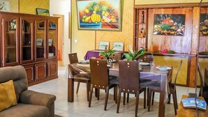 Un comedor con una mesa y sillas de madera, un aparador con puertas de cristal y obras de arte en las paredes.