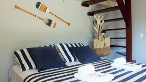 A bed with striped bedding, two pillows, and two rolled towels. - Modern loft 5 minutes from Geribá with a balcony, grill, and pool—pets welcome! (Armação dos Búzios)