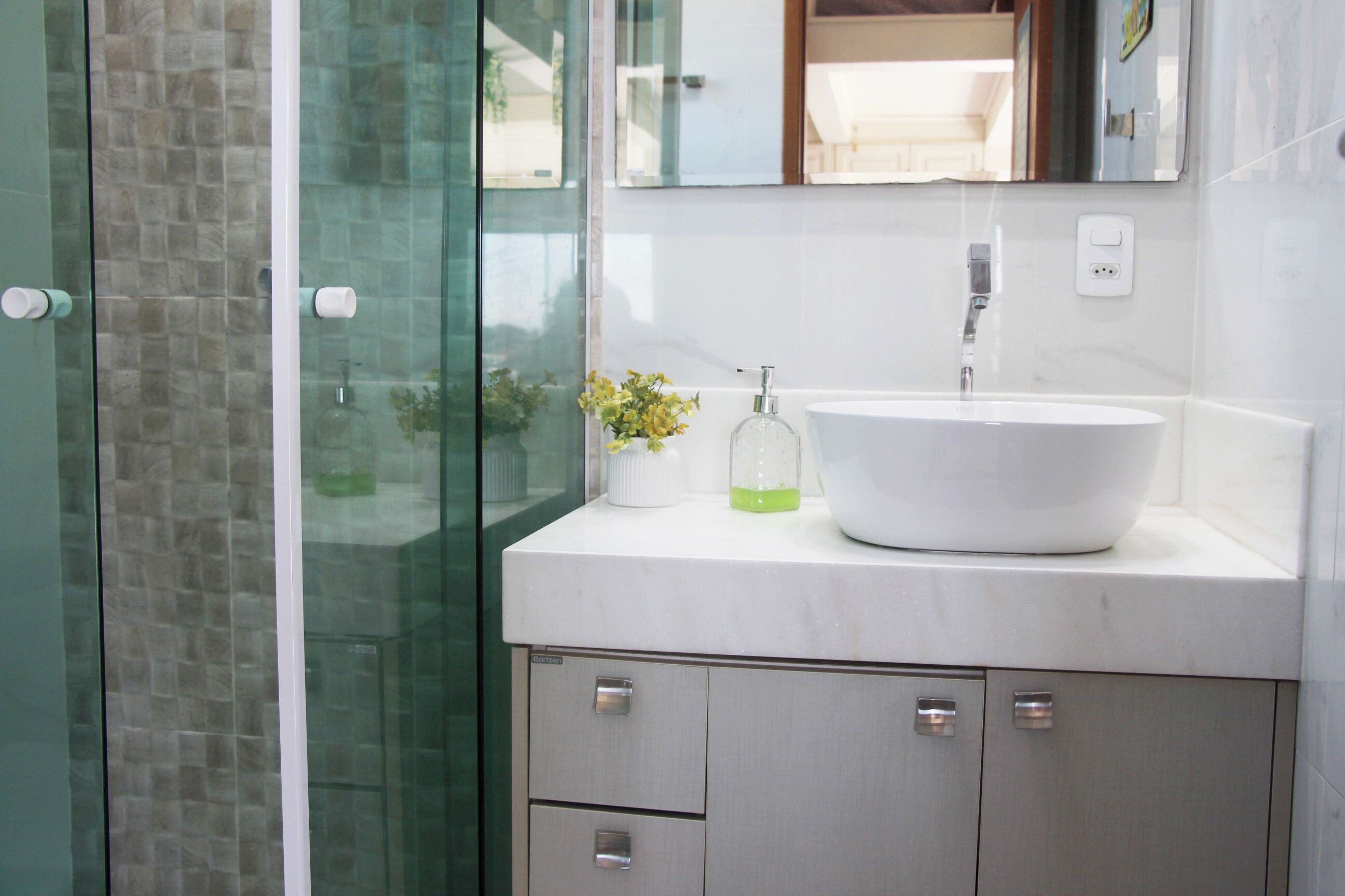 A bathroom with a glass shower enclosure, a white sink, and a mirror above it.