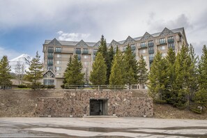Un hôtel à plusieurs étages, doté d’une façade en pierre, de balcons et offrant une vue sur une montagne enneigée.