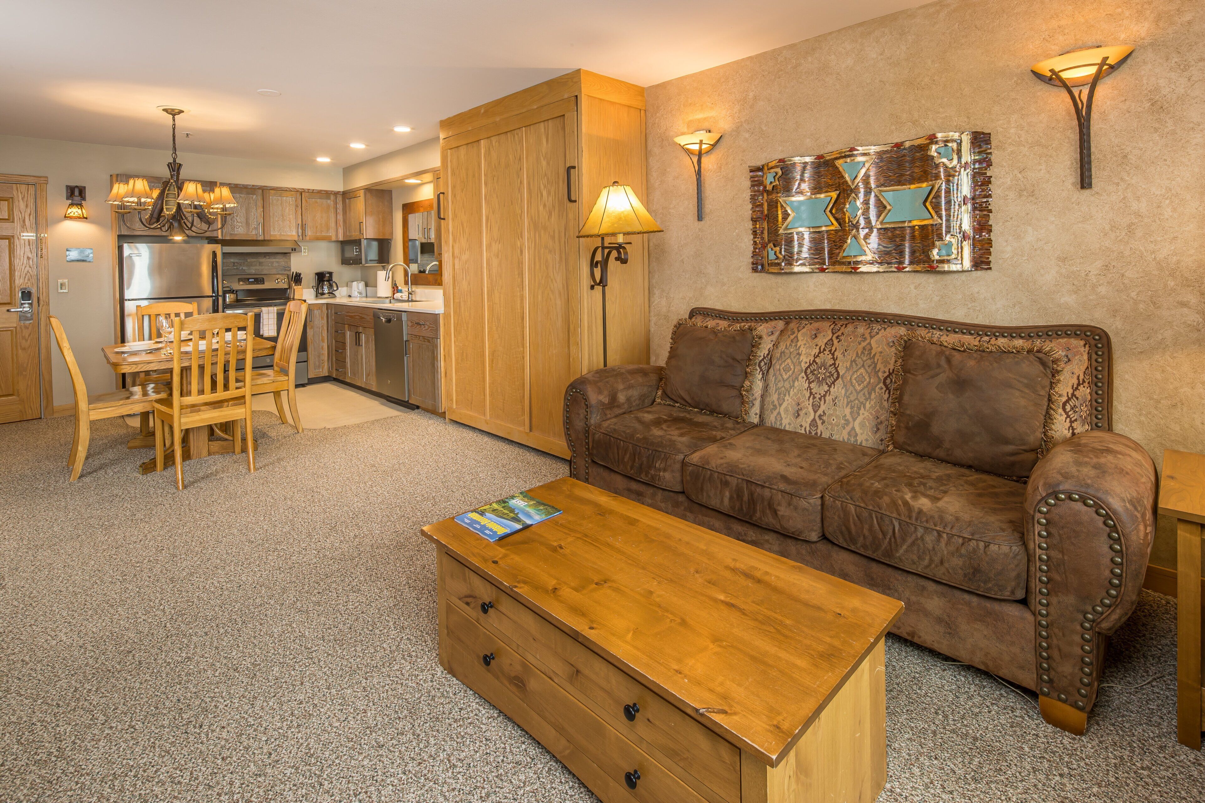 A living room with a sofa, coffee table, and dining area with chairs.