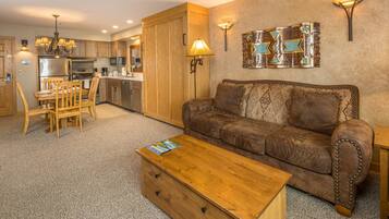 A living room with a sofa, coffee table, and dining area with chairs.