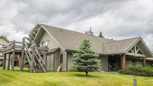 A two-story house with a covered porch, a wooden staircase, and a well-maintained lawn.